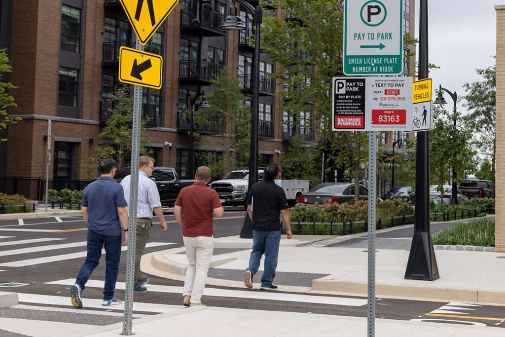 People crossing the street near parking signs