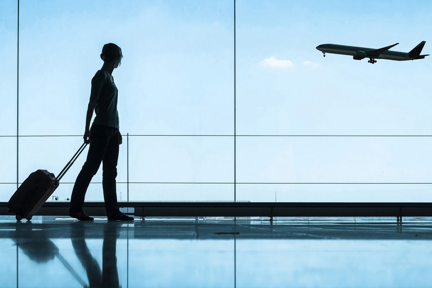 personne marchant avec des bagages à l'aéroport avec un avion en arrière-plan