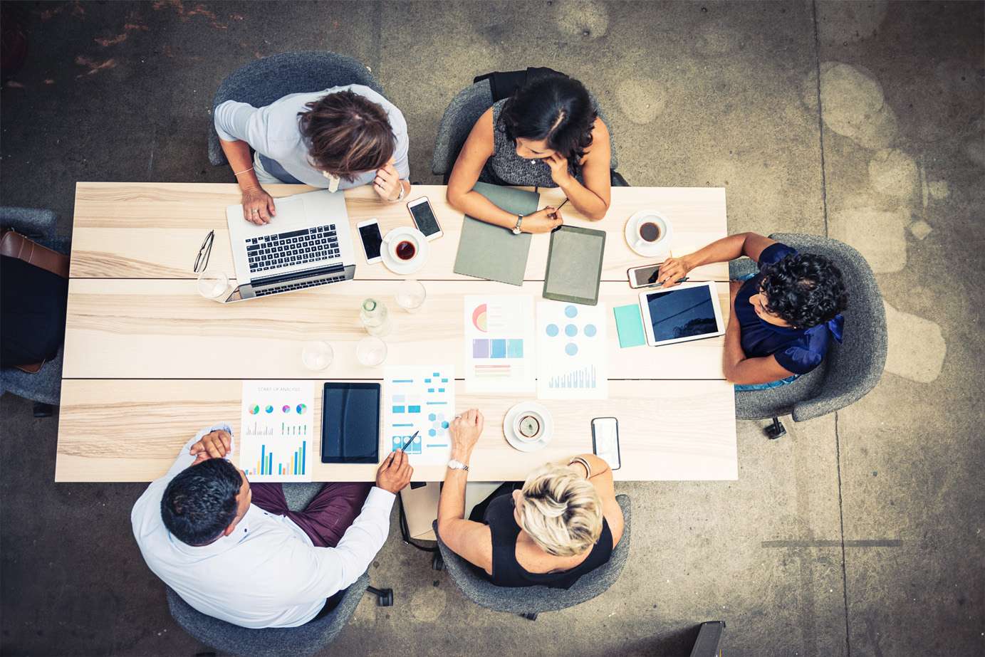 personnes travaillant à une table avec des ordinateurs