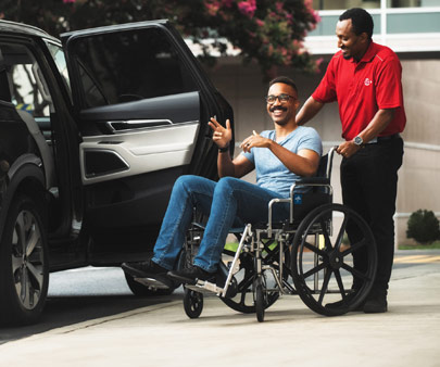 SP+ employee pushing person in wheelchair to their car