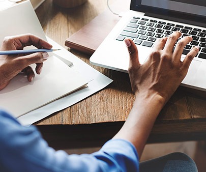 person writing and typing on a computer