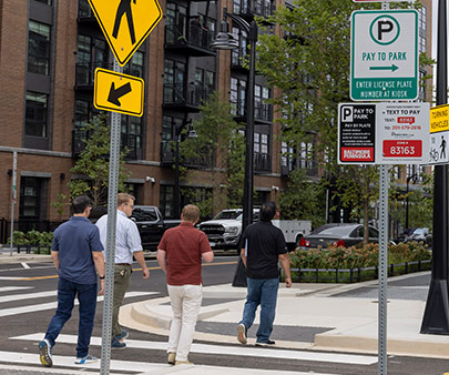 People crossing the road at a crosswalk with parking signs around