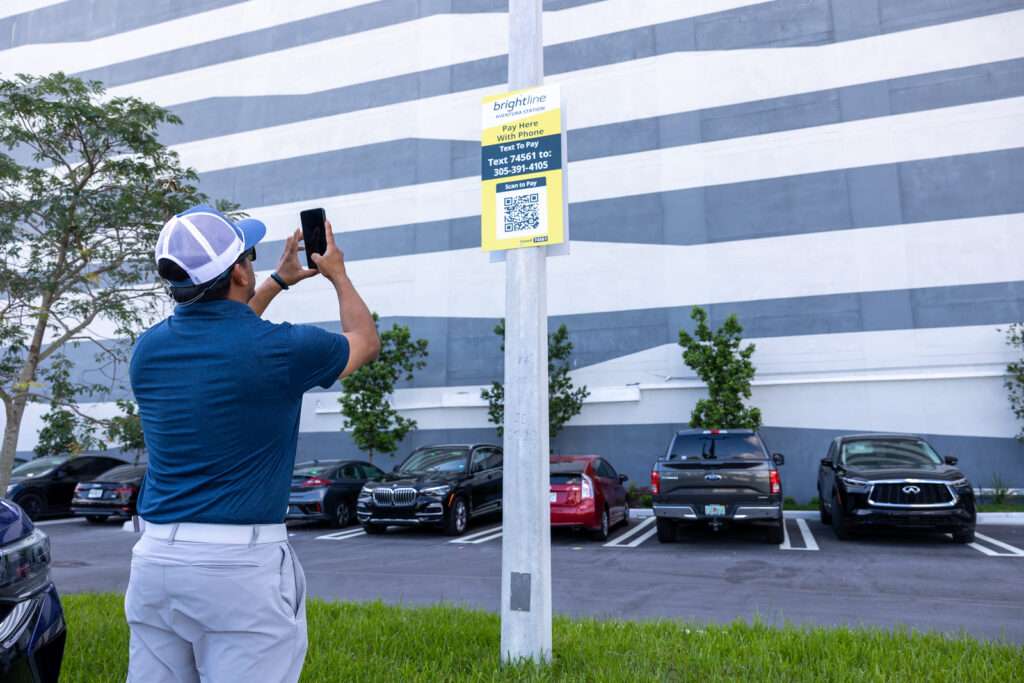 Man scaning SP+ QR code text to pay in a parking lot